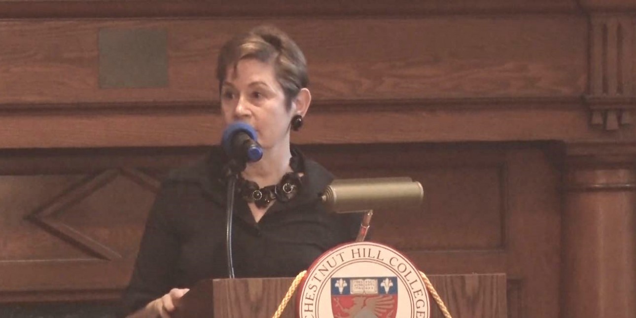 PMC's President & CEO, Maida Milone, speaking behind a podium at Chesnut Hill College