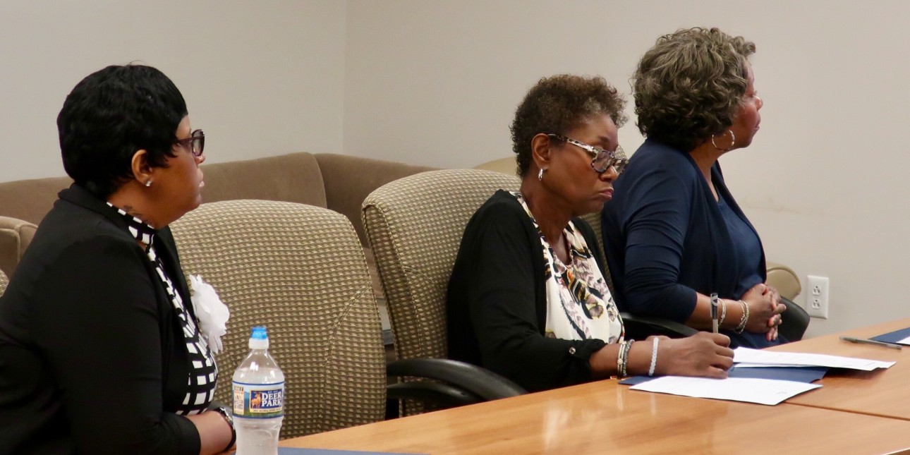 Three volunteer court watchers listening to a presentation at a training session