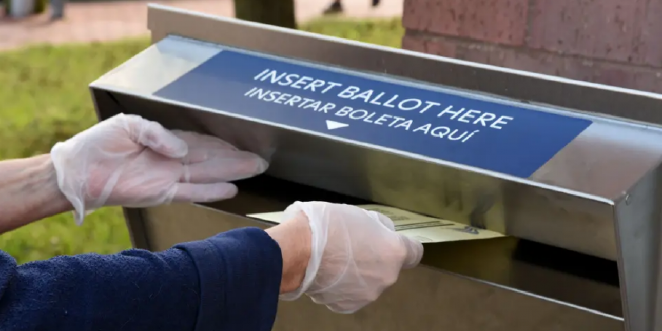 Person inserting a ballot into a drop box