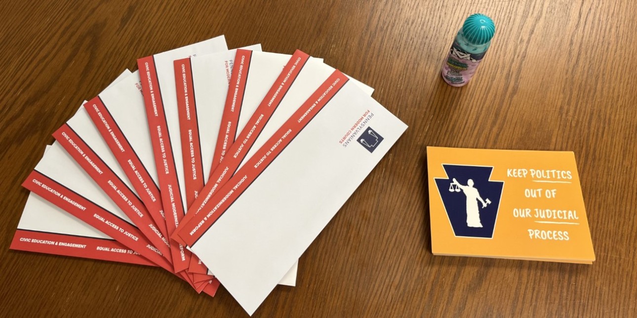 PMC envelopes, postcards to legislators, and an envelope sealer on a table