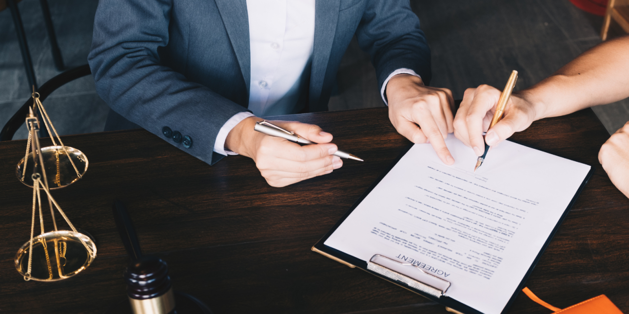 Two people reviewing a legal documents with scales of justice on the 