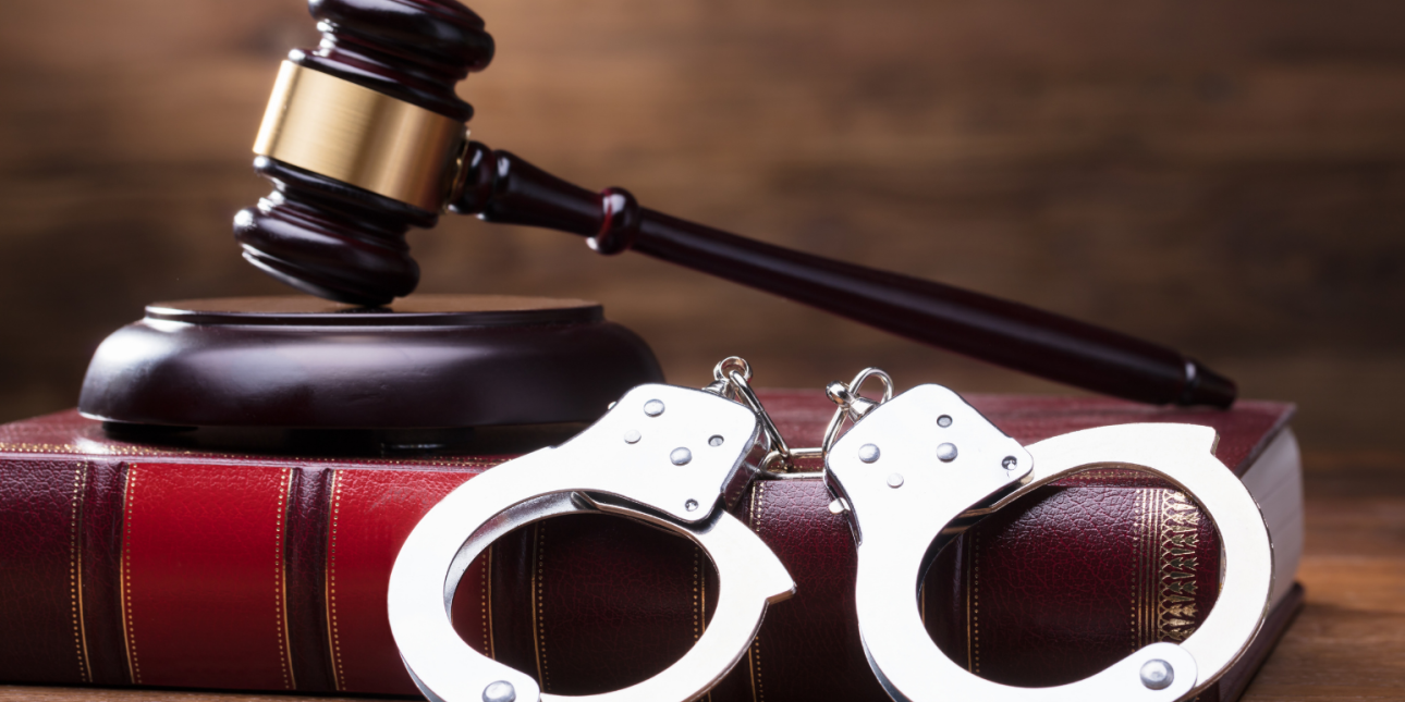 handcuffs and a gavel sitting on top of a law book