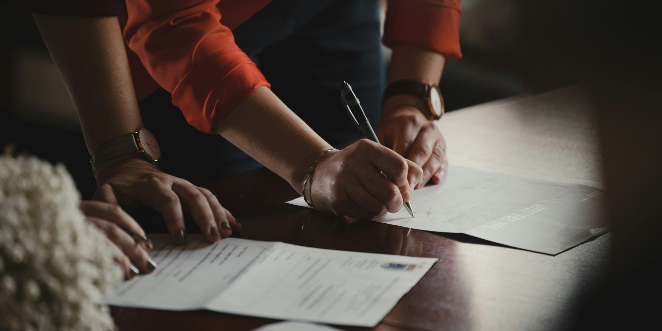 A stock image of people signing paperwork.