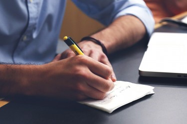 Person writing in front of a laptop