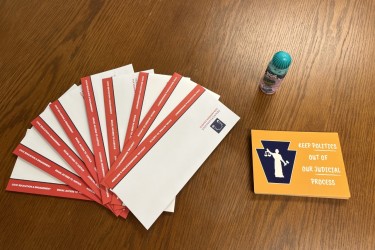 PMC envelopes, postcards to legislators, and an envelope sealer on a table